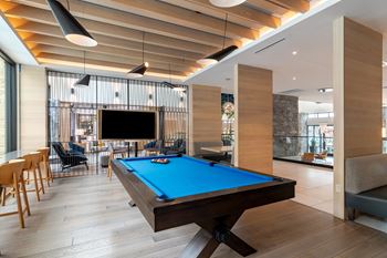 a pool table sits in the middle of a room with a tv on the wall  at Century West Pryor, Lee's Summit, Missouri